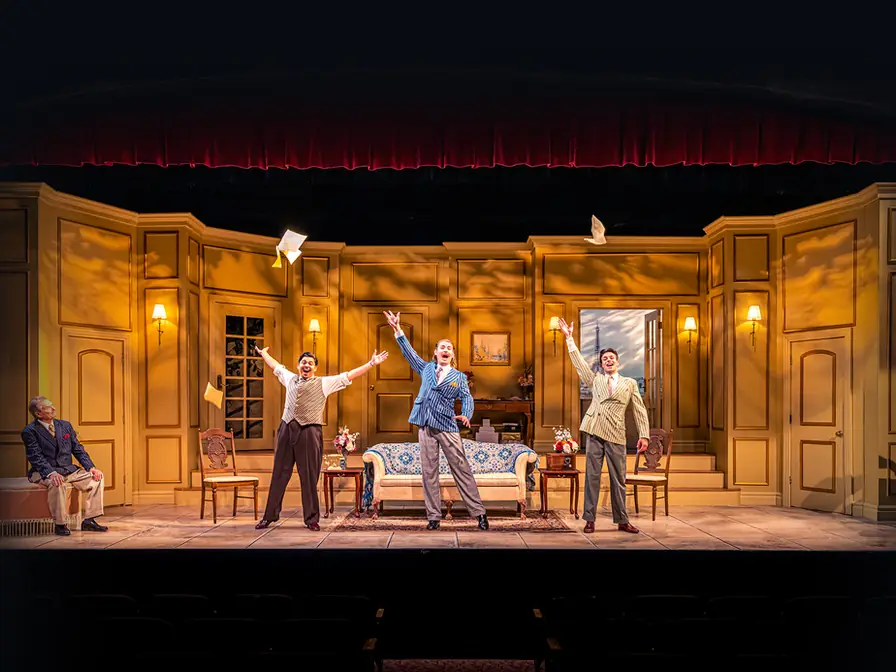 Production photo from A Comedy of Tenors showing Gretchen Ugalde's elegant amber-toned Paris hotel suite at Okoboji Summer Theatre.